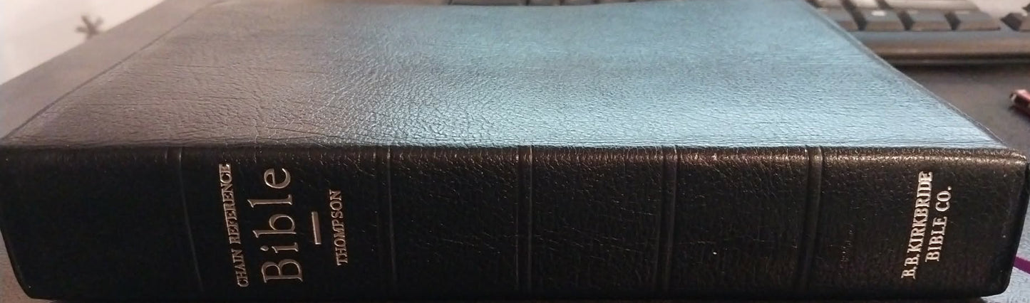 Black Bible on a desk with office equipment in the background