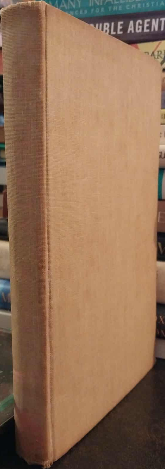 Close-up of a worn book spine with a stack of books in the background