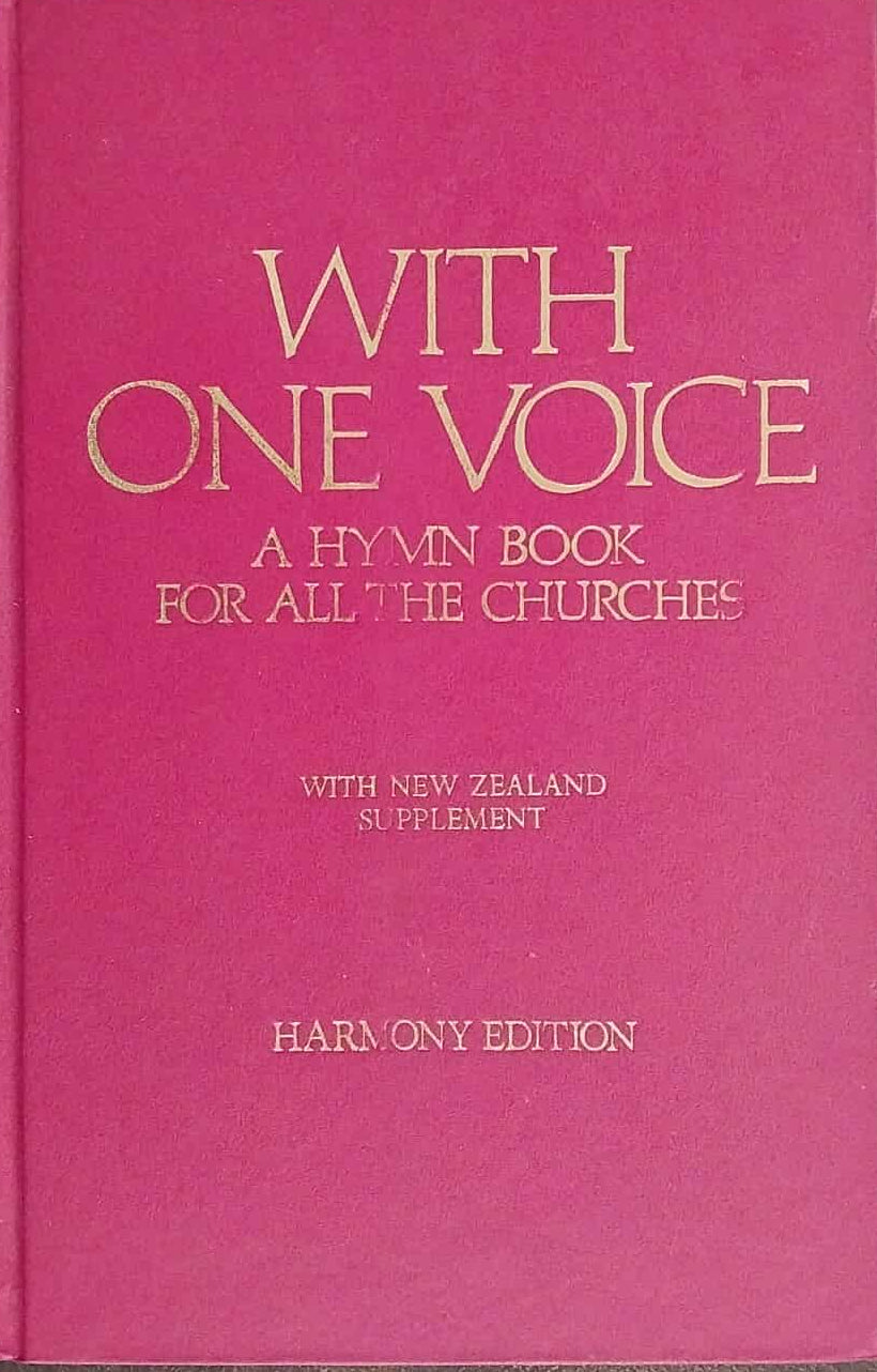 Pink hymn book titled 'With One Voice' on a dark surface