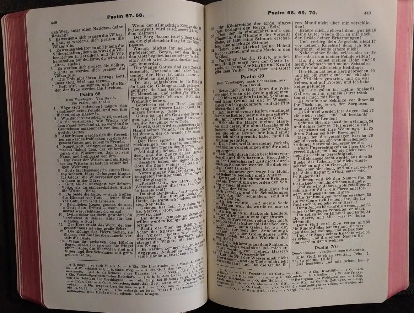 An open Bible with white pages filled with black text and pink margins, resting on a dark surface.