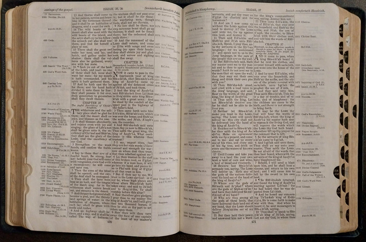 An open vintage dictionary or book with dense printed text on cream-colored pages, photographed from above on a dark wooden surface. A blue book cover is partially visible at the top edge.