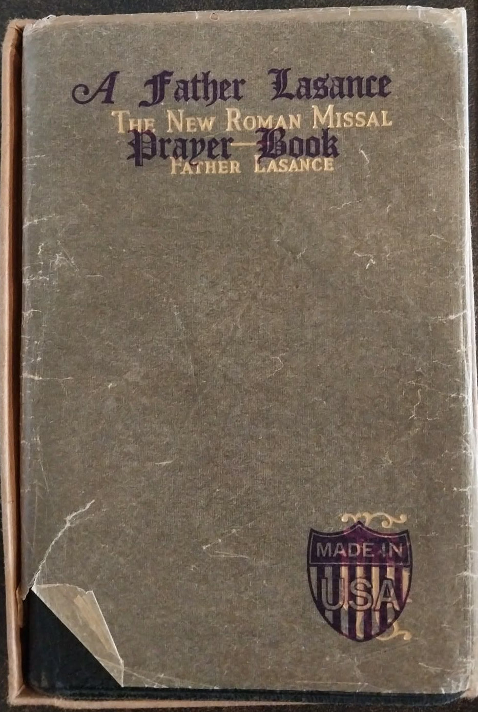 Vintage prayer book titled 'A Father Lasance The New Roman Missal Prayer Book' with a USA shield on a dark surface.