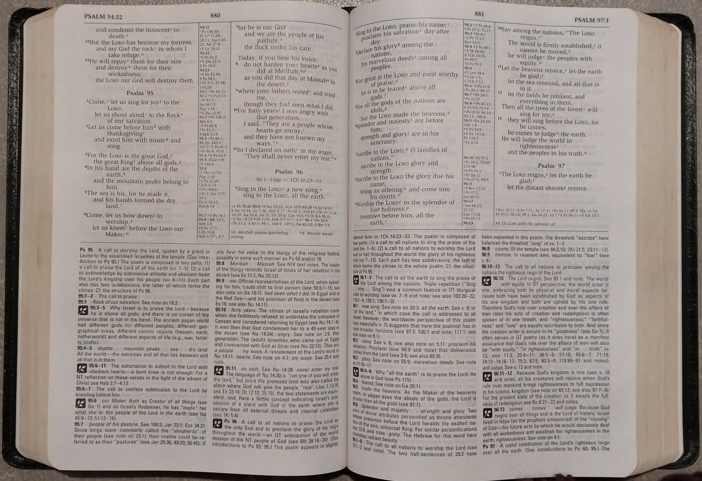 An open hardcover Bible with printed text pages, photographed from above on a gray textured surface.