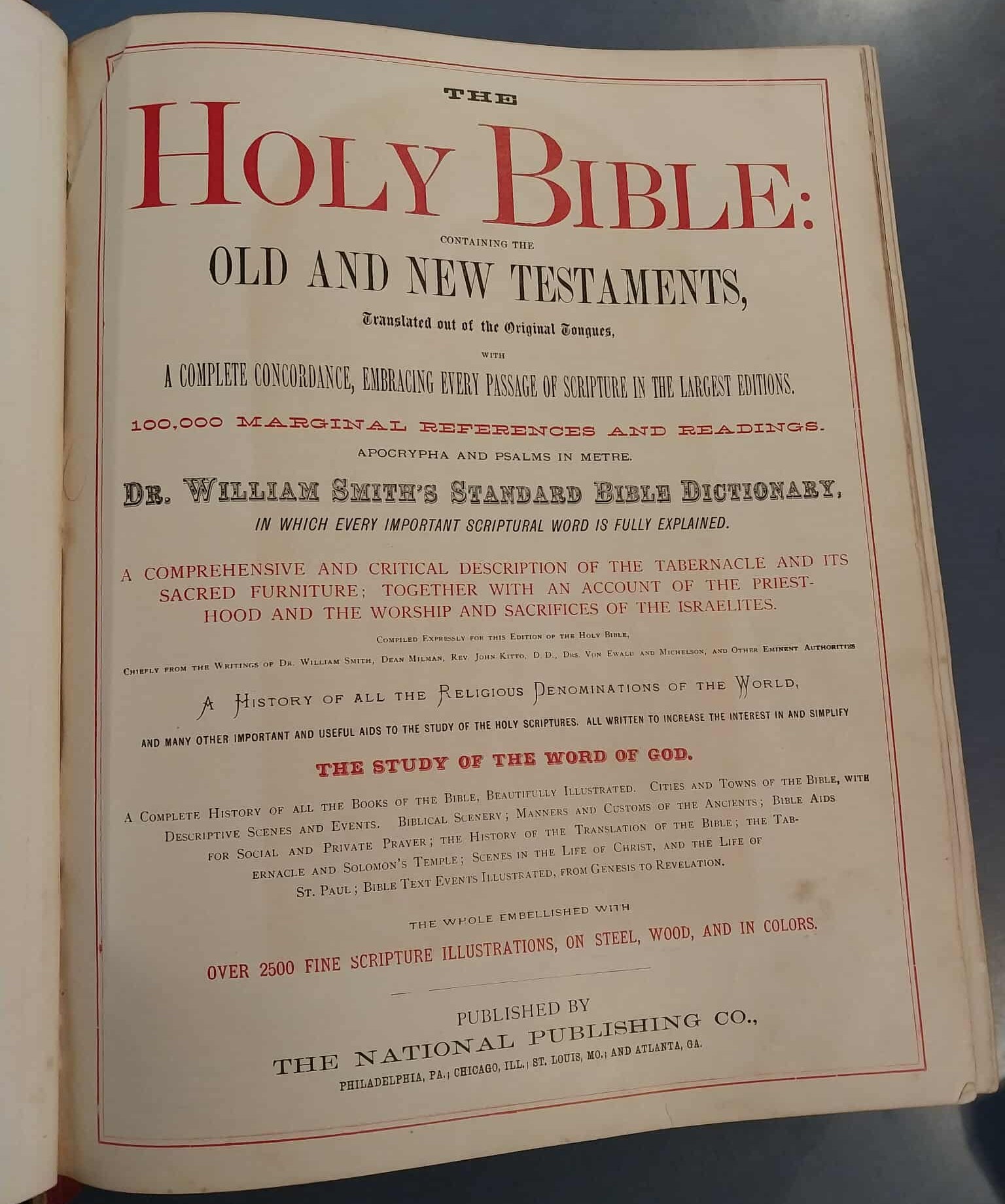 Open book with title page of 'The Holy Bible' on a dark surface