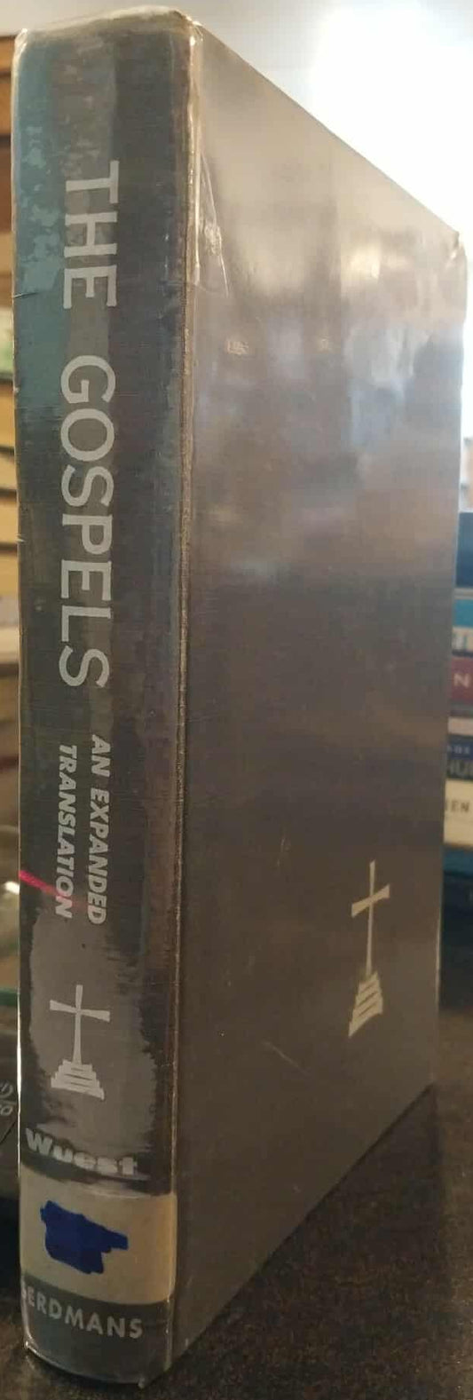 Book titled 'The Gospels' with a cross symbol on a shelf.