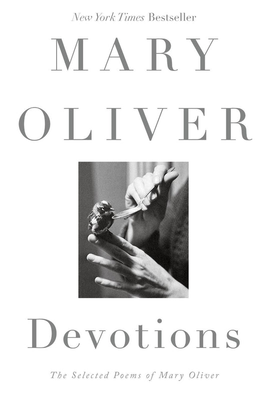 Book cover of 'Devotions' by Mary Oliver with a black and white photo of a hand holding a flower.