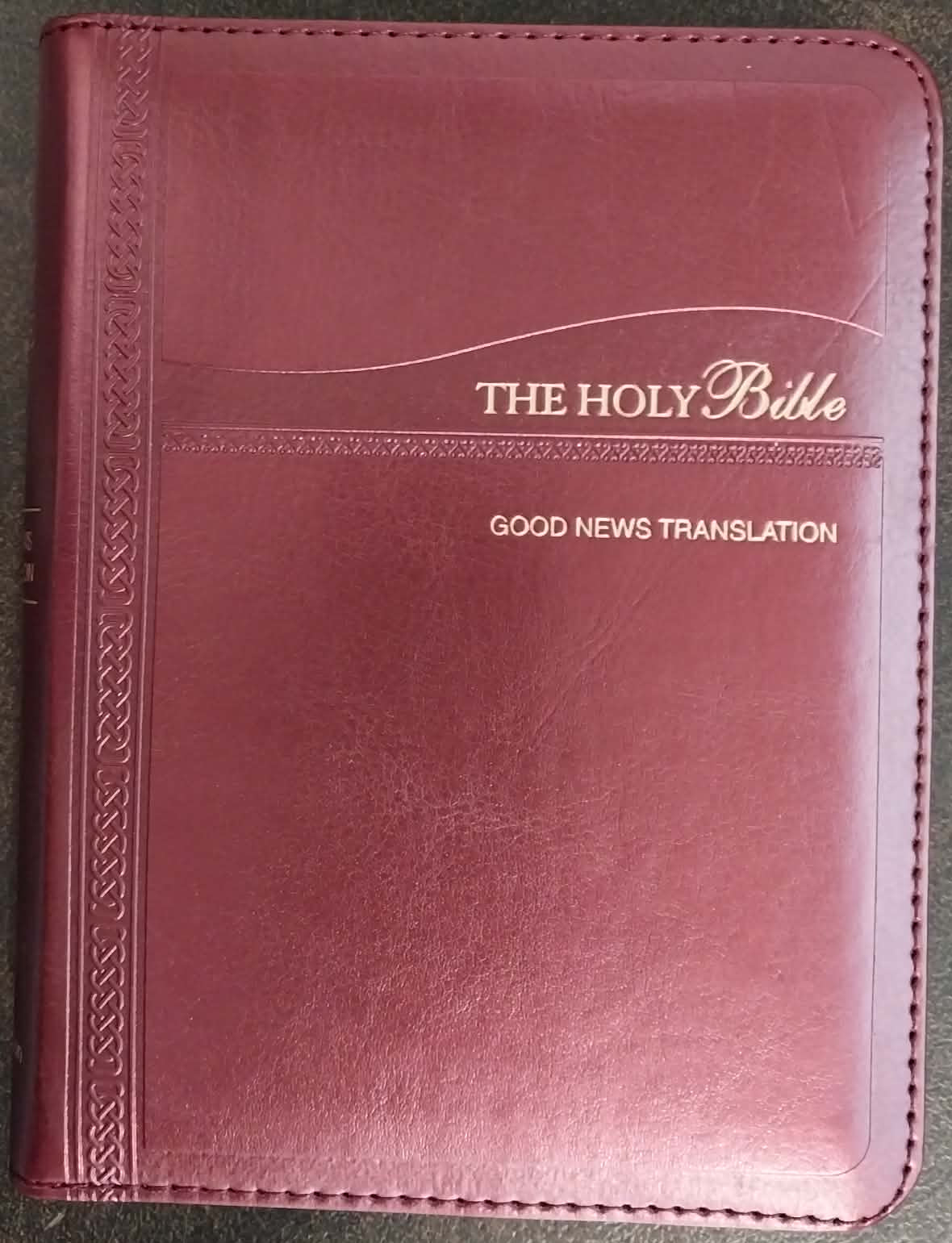 Maroon Bible cover with 'The Holy Bible Good News Translation' text on a dark surface