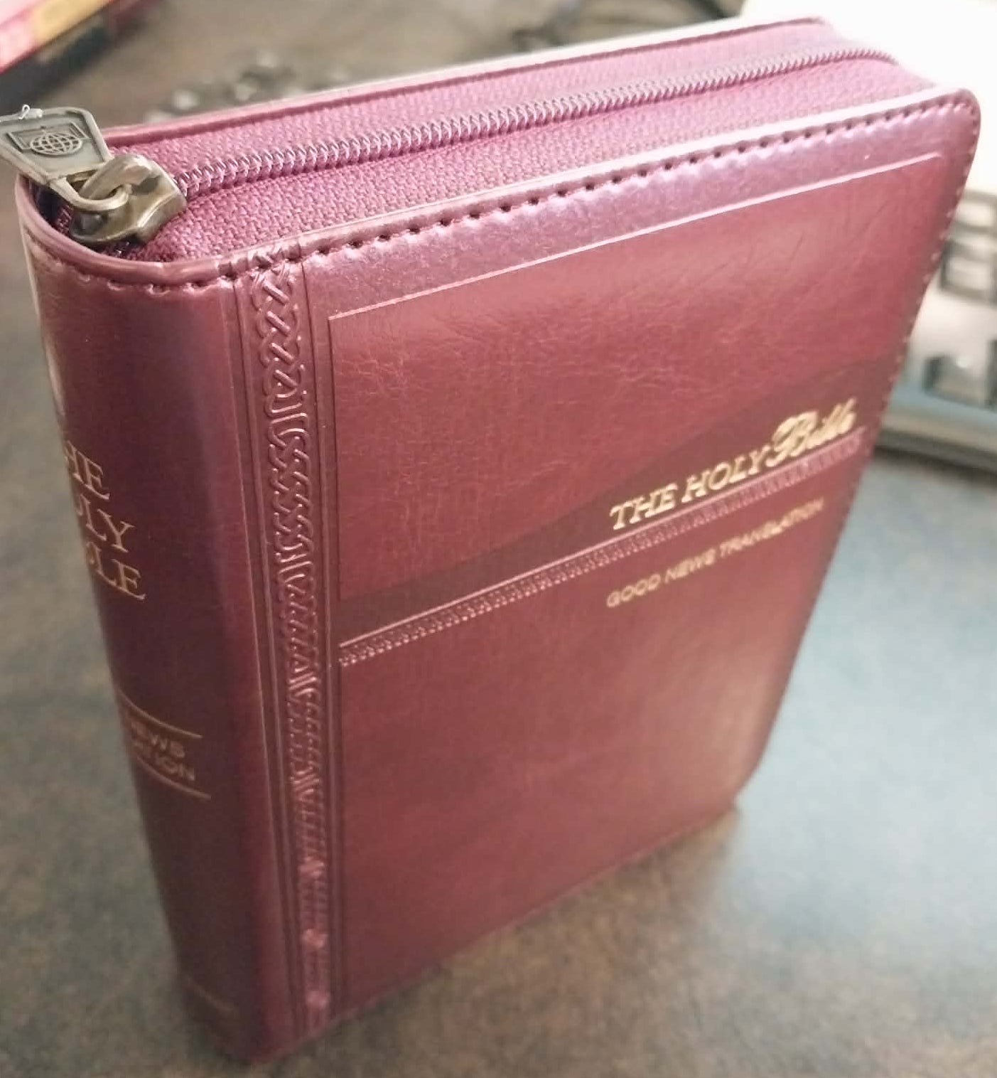 Maroon leather-bound book with gold text on a reflective surface