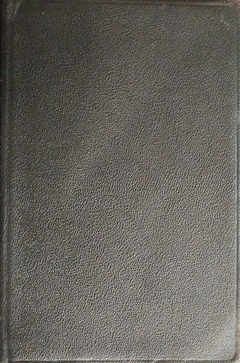 A black textured leather journal or notebook cover shown from a top-down view on a dark brown textured surface.