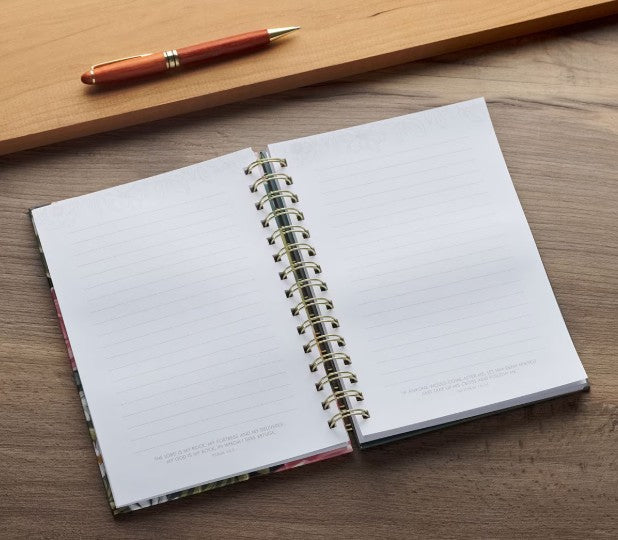 Open spiral-bound notebook on a wooden surface with a pen next to it