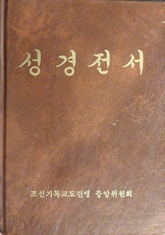 A brown leather-bound book with gold Korean text on the cover, photographed from above on a dark textured surface.