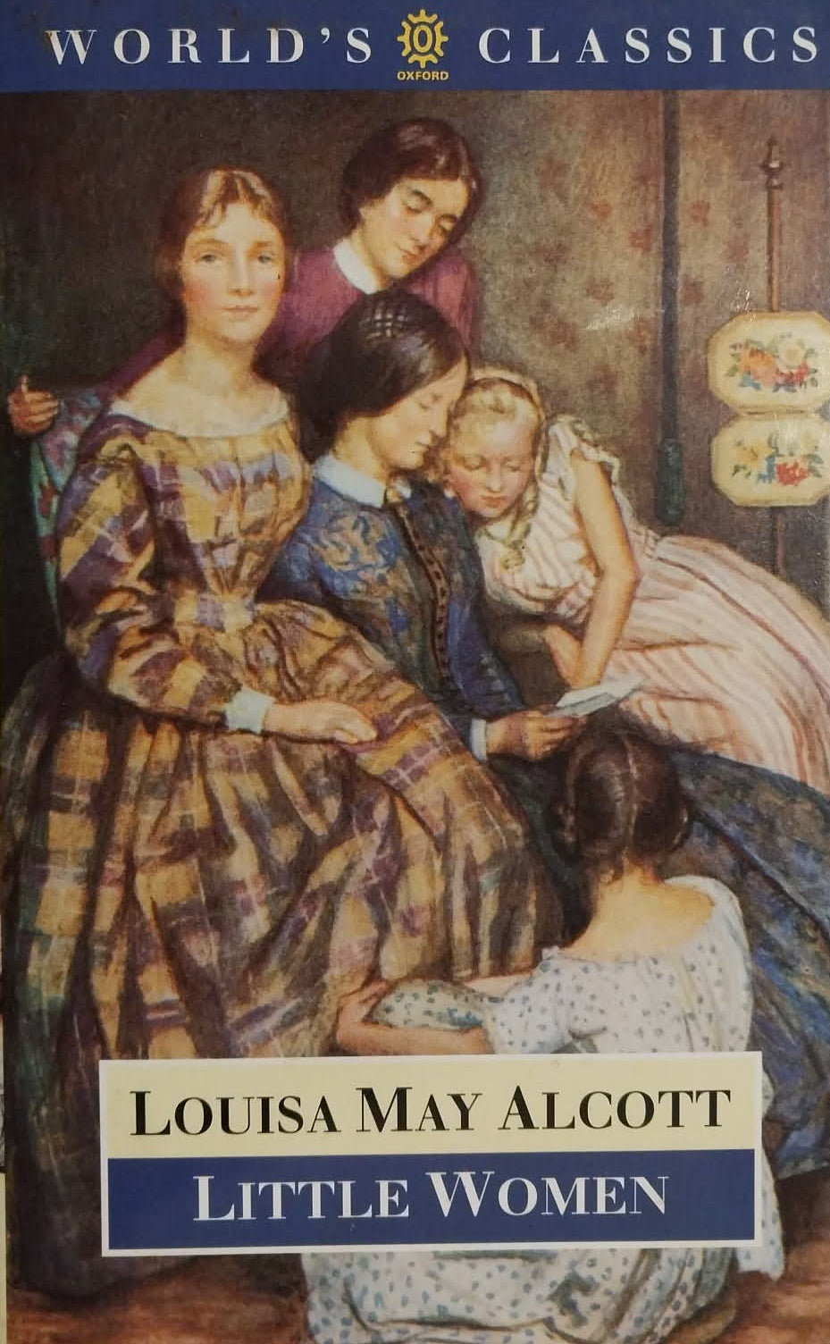 A World's Classics edition of Louisa May Alcott's 'Little Women' book, showing the illustrated cover with four women in historical dress against a dark interior background.