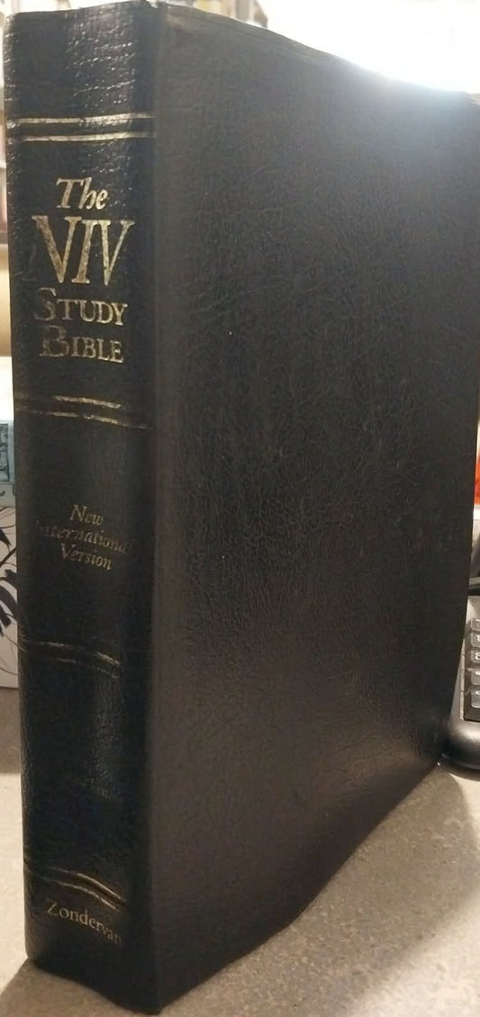 A black leather-bound copy of The New International Version (NIV) Study Bible standing upright on a desk, with gold lettering on the spine.