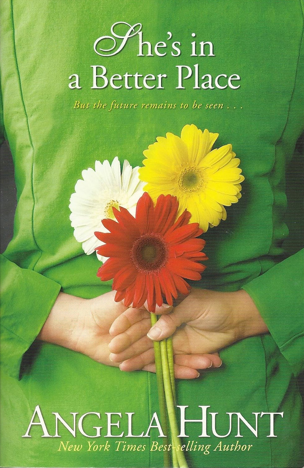 Book cover for 'She's in a Better Place' by Angela Hunt, featuring a green-clad person holding red, yellow, and white daisies. The title and author name are printed in white text.