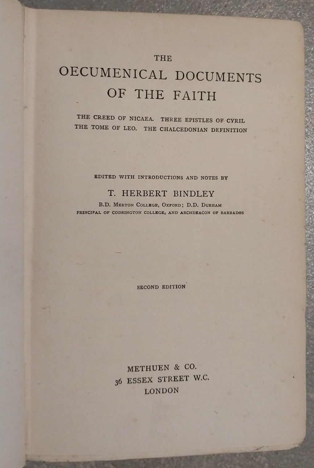 An open vintage book showing the title page of 'The Oecumenical Documents of the Faith' with printed text on aged cream paper, photographed against a textured gray background.