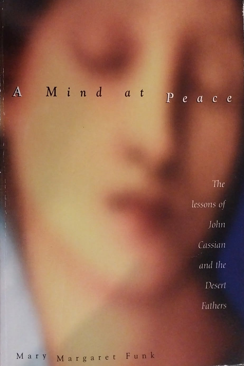 The book cover of 'A Mind at Peace' by Mary Margaret Funk, featuring a soft-focus portrait of a face in warm beige and brown tones, displayed on a dark textured background.
