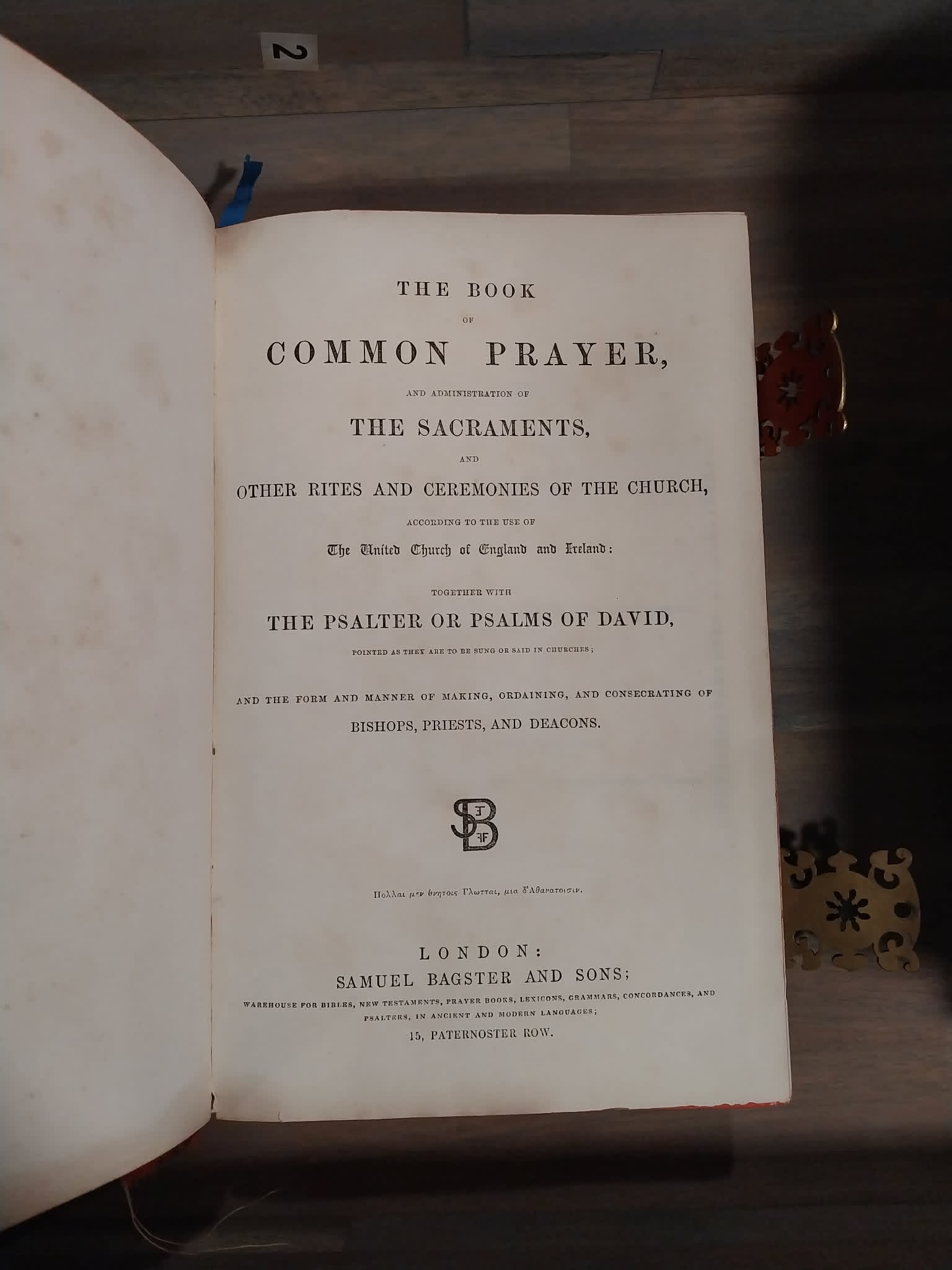 An open vintage book showing the printed title page for 'The Book of Common Prayer' on aged off-white paper, photographed on a dark wooden surface.