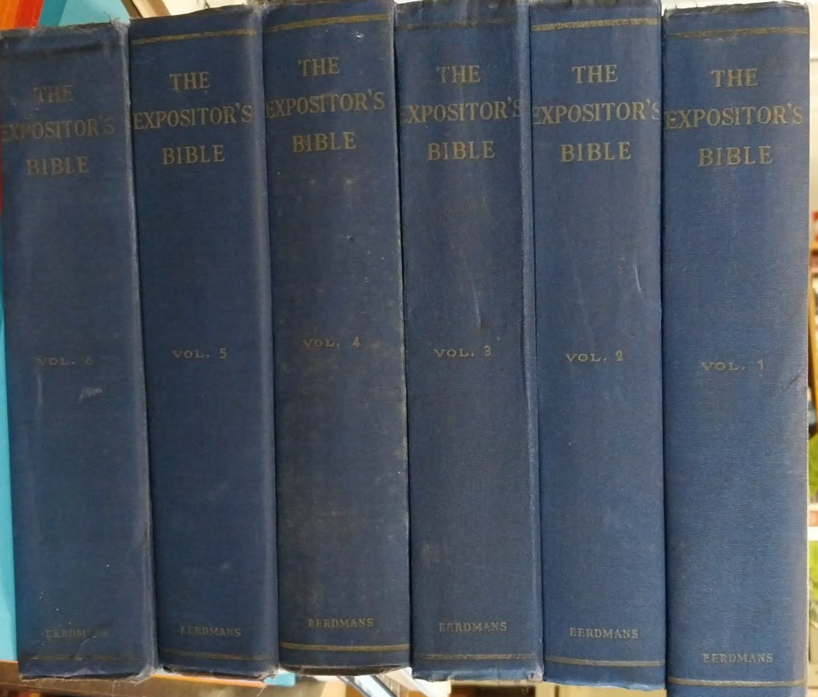 Stack of blue books on a colorful surface with bookshelves in the background