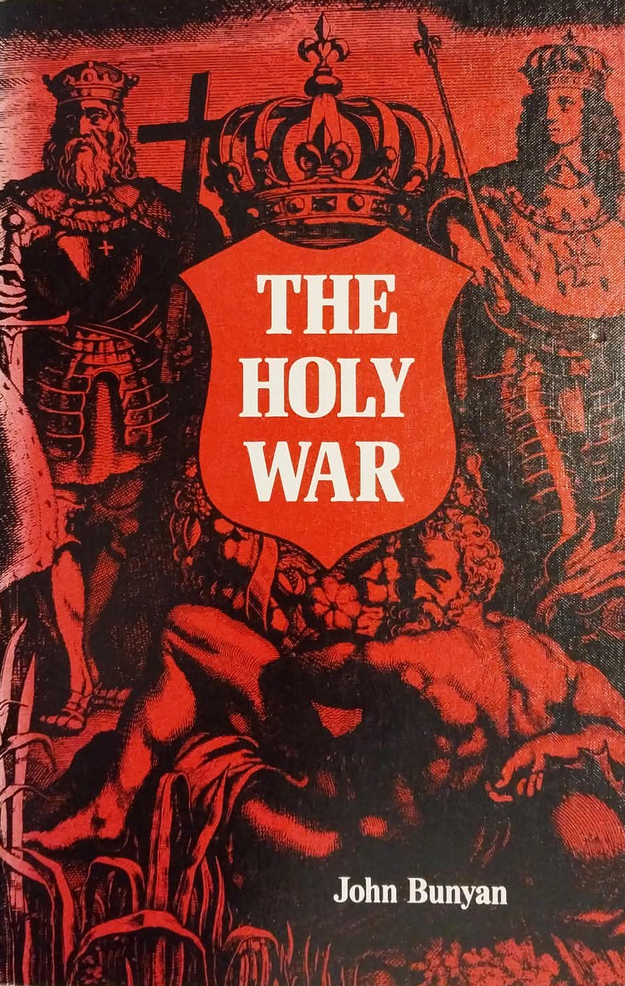 A book titled 'The Holy War' by John Bunyan, featuring a red and black illustrated cover with a central red shield and white title text, photographed on a light surface.
