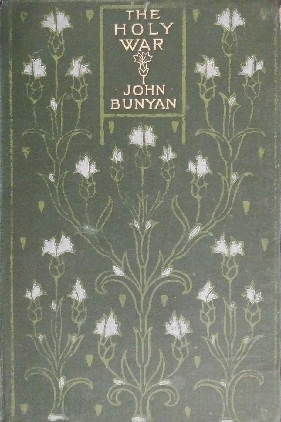 Vintage hardcover book of 'The Holy War' by John Bunyan, featuring a dark olive green cover with white floral illustrations and gold lettering, resting on a dark brown textured surface.