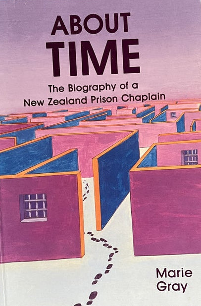 The book cover of 'About Time: The Biography of a New Zealand Prison Chaplain' by Marie Gray, featuring a stylized illustration of pink and blue buildings, photographed on a textured blue background.