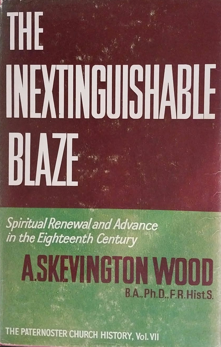 The Inextinguishable Blaze book by A. Skevington Wood, featuring a maroon and green cover with white text, photographed on a dark textured surface.