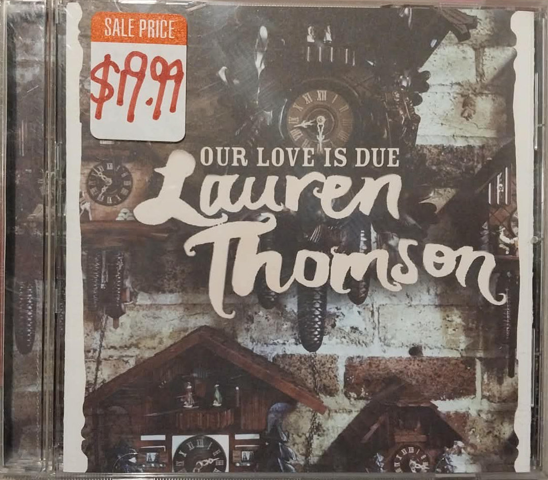 A physical copy of Lauren Thompson's CD album 'Our Love Is Due' in a clear jewel case, resting on a gray textured surface. A red '$9.