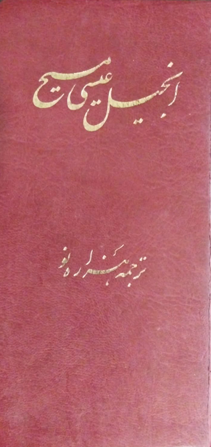 A red hardcover book with gold Arabic calligraphy on the front, photographed from above on a dark textured surface.
