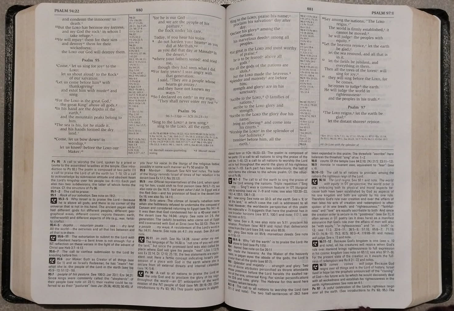 An open hardcover Bible with printed text pages, photographed from above on a gray textured surface.