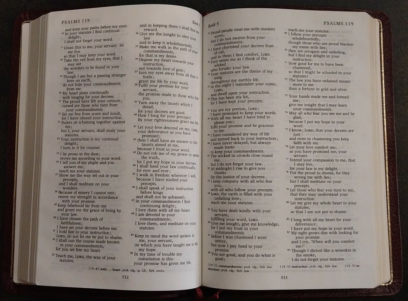 An open book with dense columns of black text on white pages, photographed from above on a dark surface.