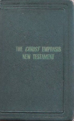 A dark green leather-bound New Testament book titled 'The Christ Emphasis New Testament' with gold lettering on the cover, set against a textured pinkish-beige background.