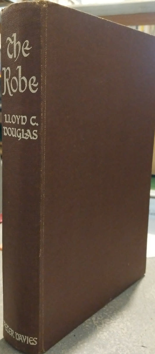 A brown hardcover book titled 'The Robe' by Lloyd C. Douglas, standing upright on a tabletop in an indoor setting.